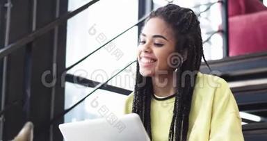 特写非常漂亮的非洲年轻女士在电脑上工作，在商务中心，她坐在楼梯上，<strong>还有</strong>一个